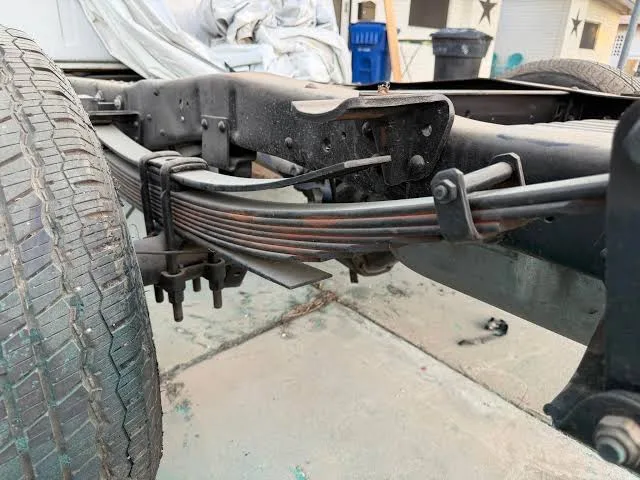 Close-up of the factory rear suspension on our Project ’72 bumpside: the leaf spring pack rides over the axle tube, U-bolts strapped over the pack — the stock setup before the flip