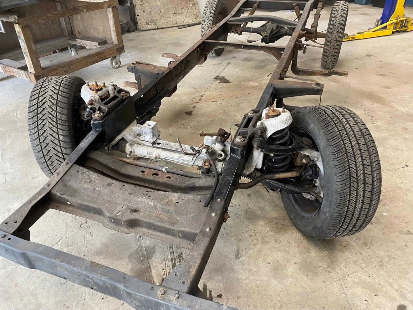 Bare F-100 frame with the Crown Victoria aluminum front crossmember, rack-and-pinion steering and coil springs installed